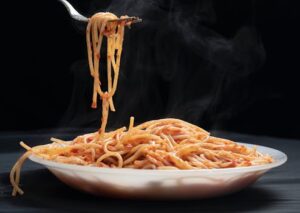 Hot spaghetti with rich tomato sauce twirled on a fork, exuding delicious aroma.